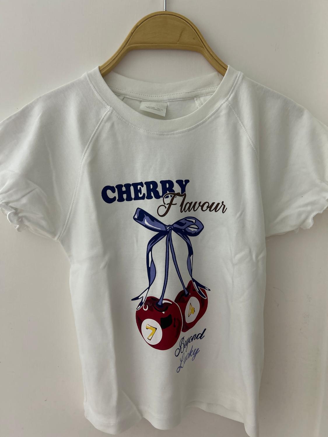 White t-shirt hanging with a design of red cherries and text "CHERRY Flavour" and "Beyond Lucky" in blue and brown.