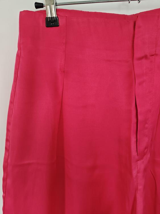 Fuchsia skirt hanging on a metal hanger, showing stitching details and soft texture. White background.