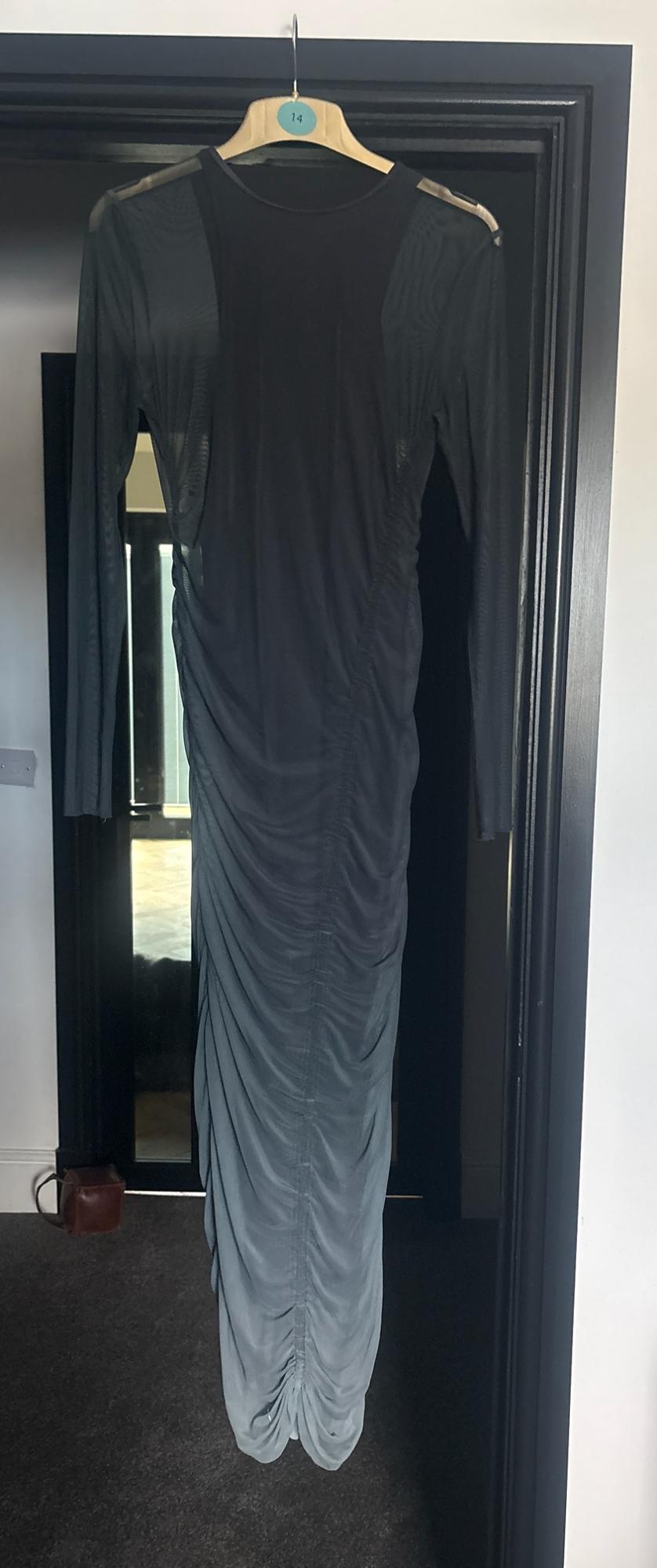 Grey maxi dress with semi-transparent sleeves and ruched detailing, hanging on a hanger with the number 14 in a black door frame.