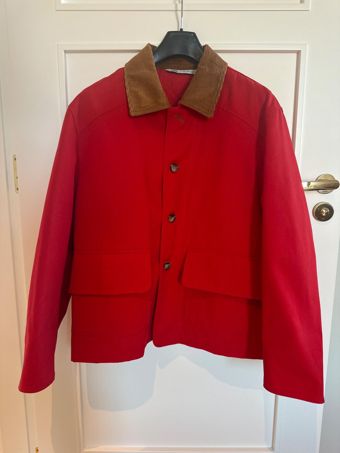 Front view of a red jacket with a brown corduroy collar and front flap pockets.