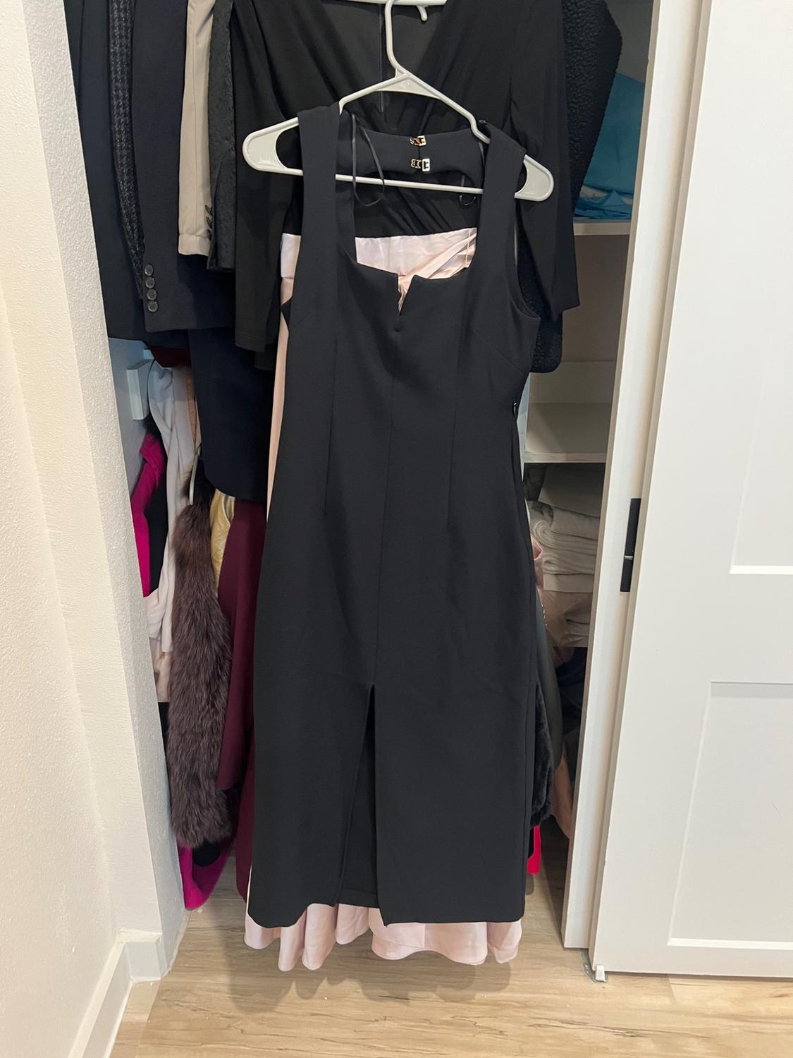 Front view of a black sleeveless dress with a square neckline and front slit.