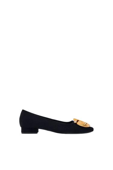 Side view of a black shoe with gold detail on the front.