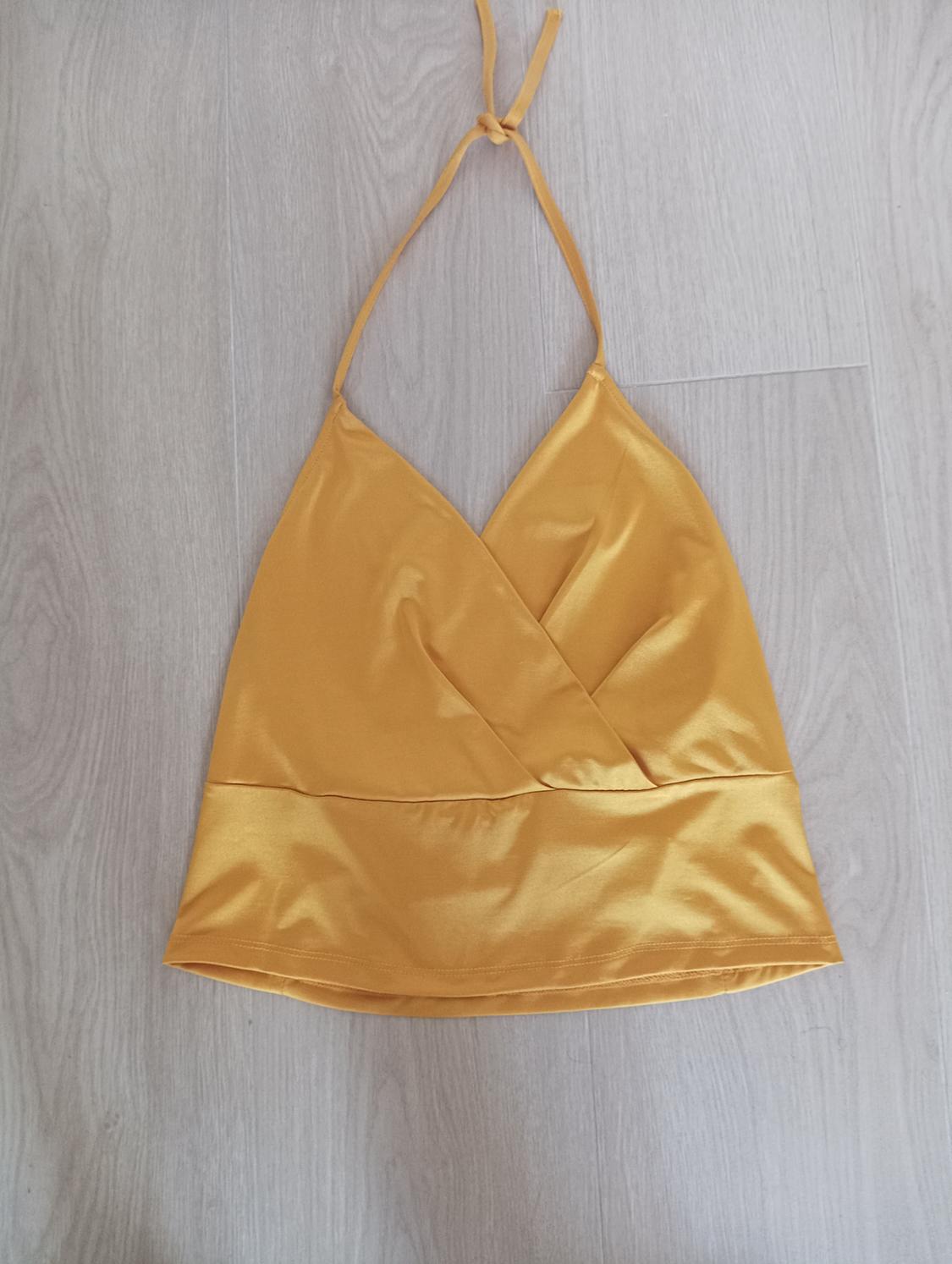 Yellow camisole with thin straps and a V-neckline on a light wood background.