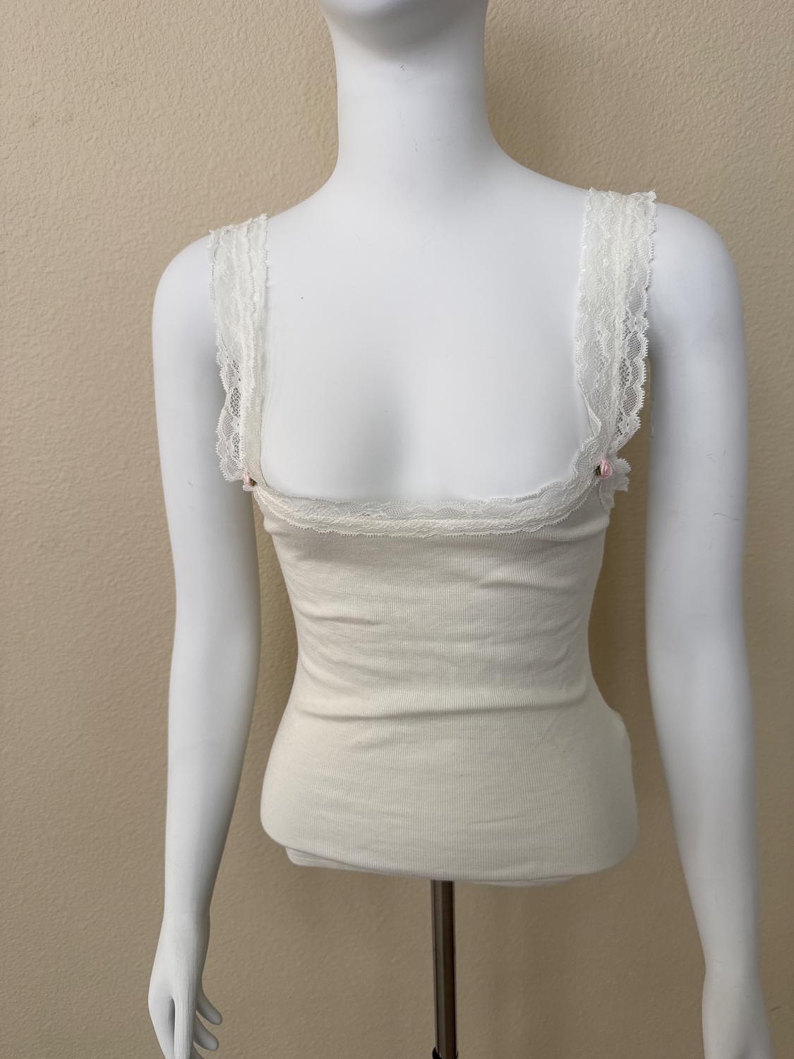 White mannequin wearing a cream ribbed camisole with lace trim and small roses, against a beige background.