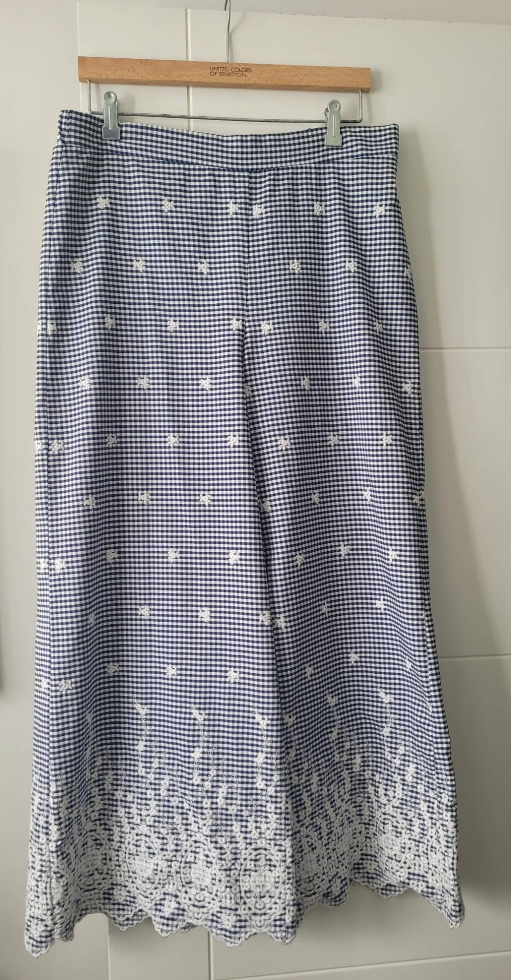 Blue and white checked skirt with white floral embroidery on the hem, hanging on a "United Colors of Benetton" hanger.