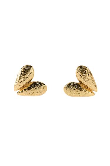 Gold-coloured leaf-shaped drop earrings with a textured finish on a black background.
