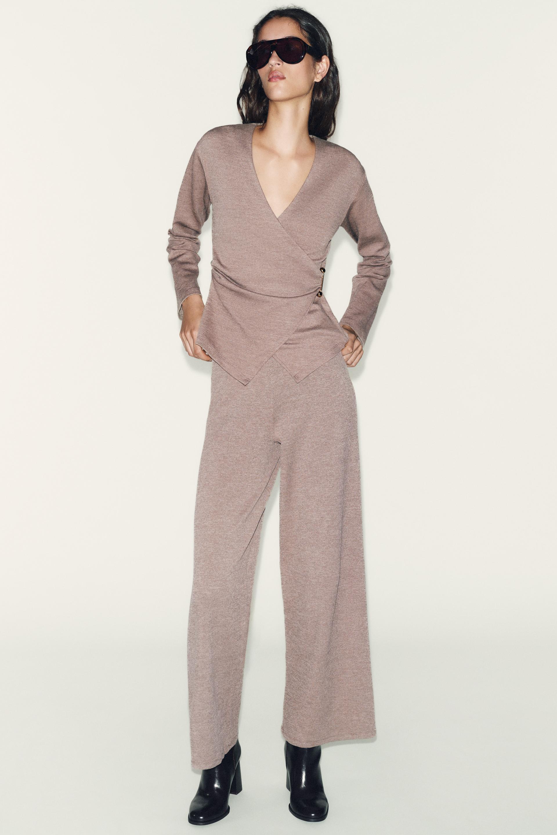 Dark anthracite wrap top with side clasp and long sleeves, matching wide-leg pants, and black ankle boots.