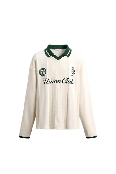 Front view of an polo shirt with a green collar. "Union Club" text and embroidery on the chest. Long sleeves with green cuffs.