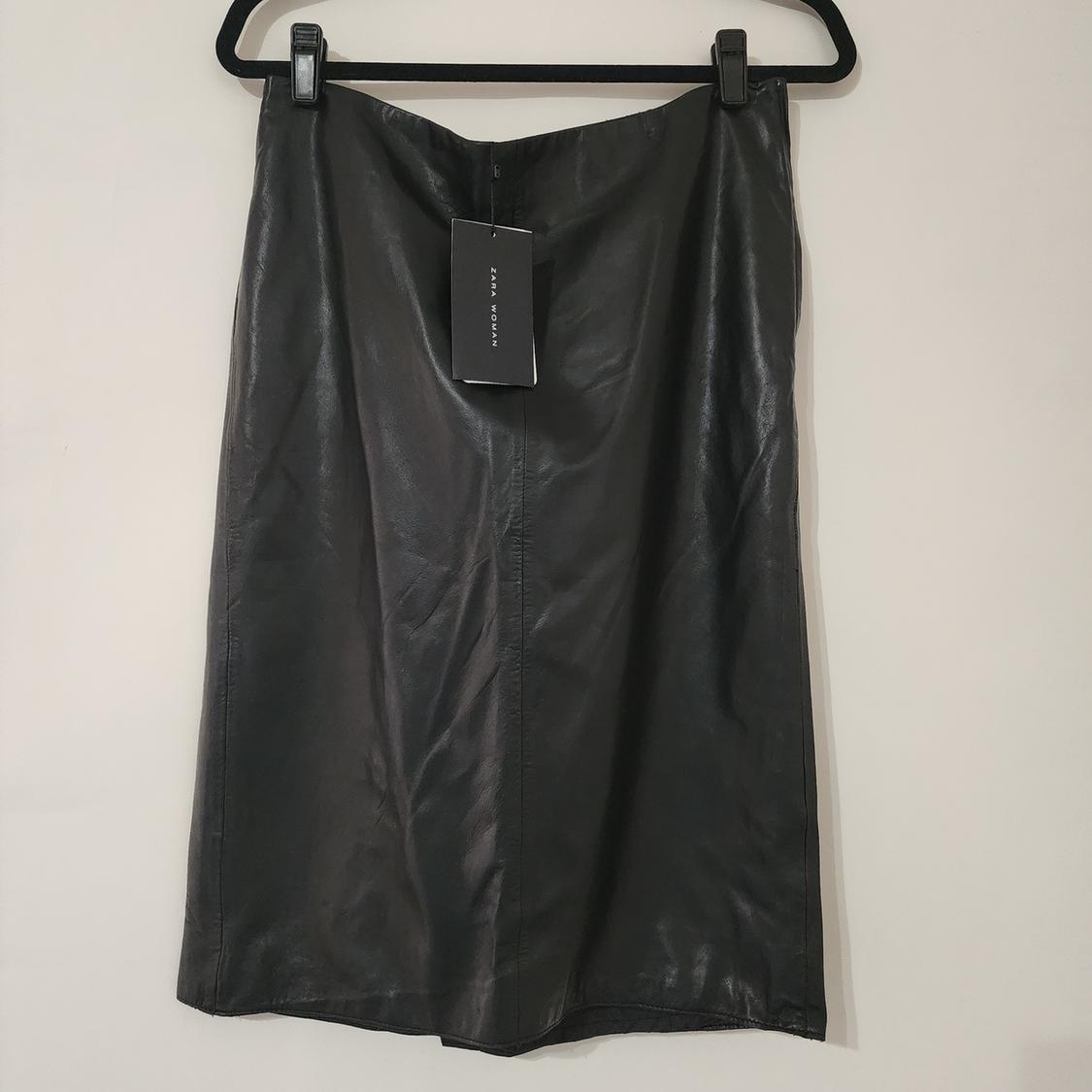 Front view of a black skirt with a label, center seam, and straight cut.