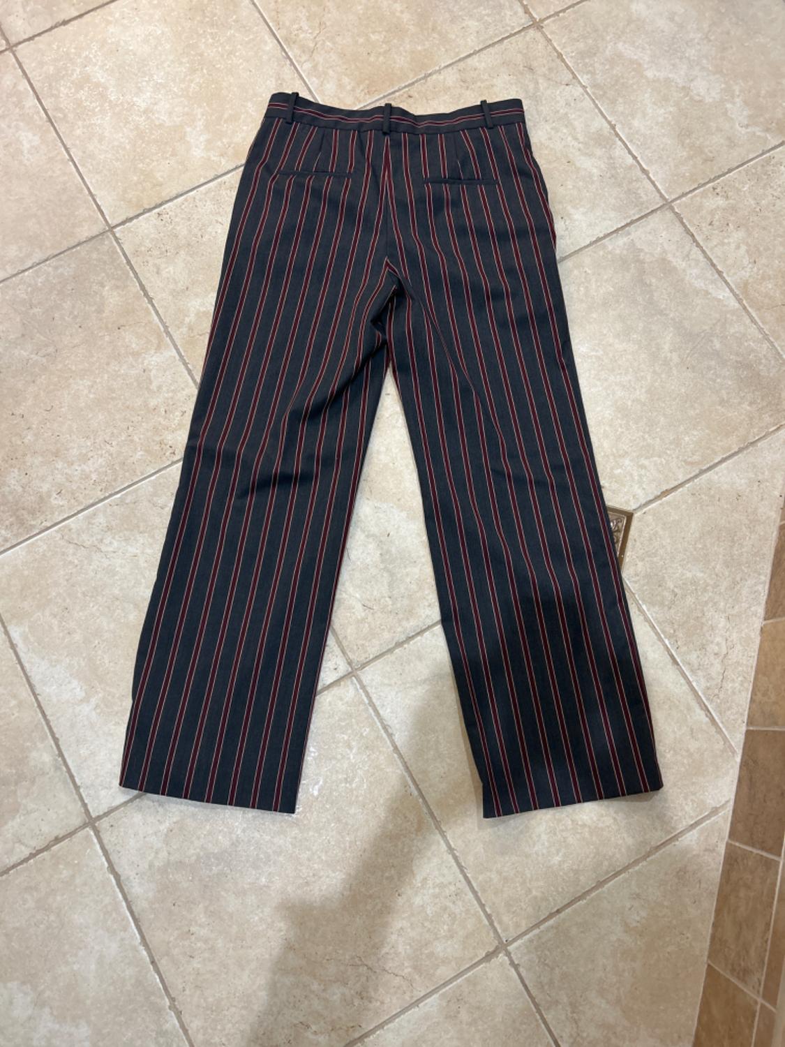 Back view of black pants with red vertical stripes and back pockets.