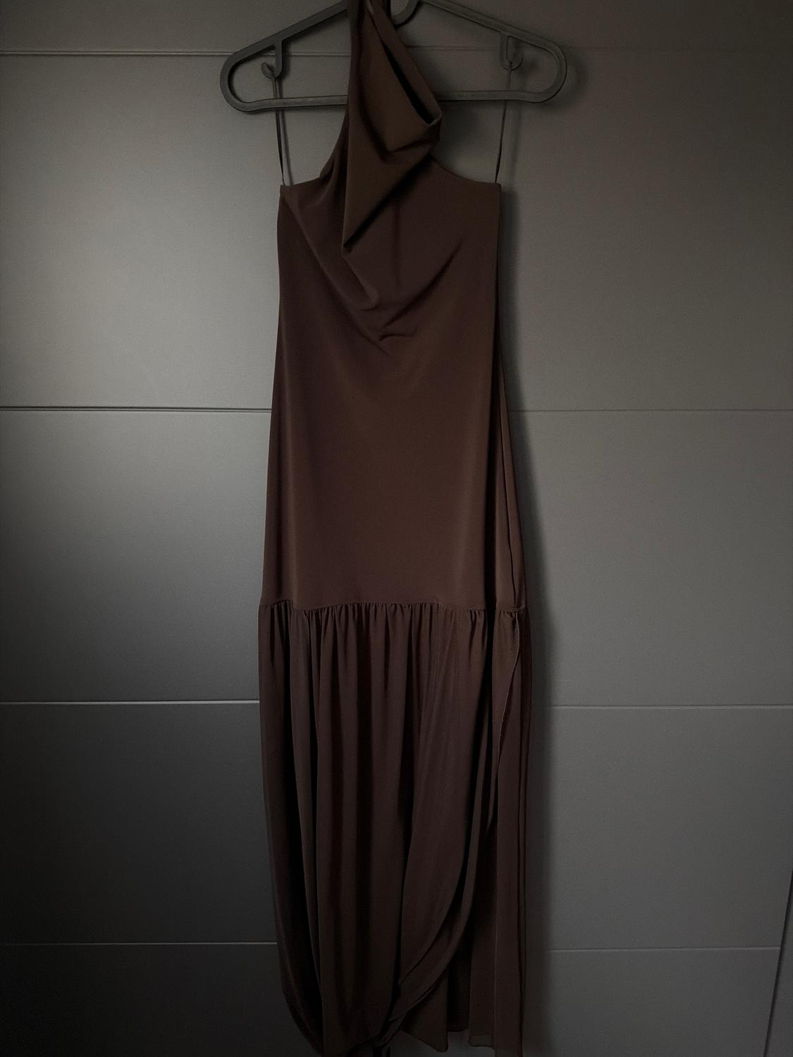 Brown sleeveless dress hanging on a hanger against a dark grey background.
