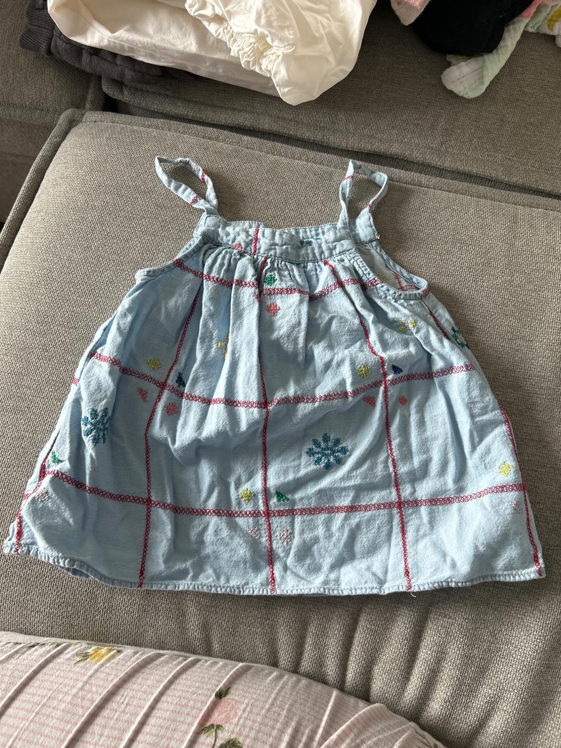 Light blue sundress with red check print and small floral motifs, on a grey sofa.