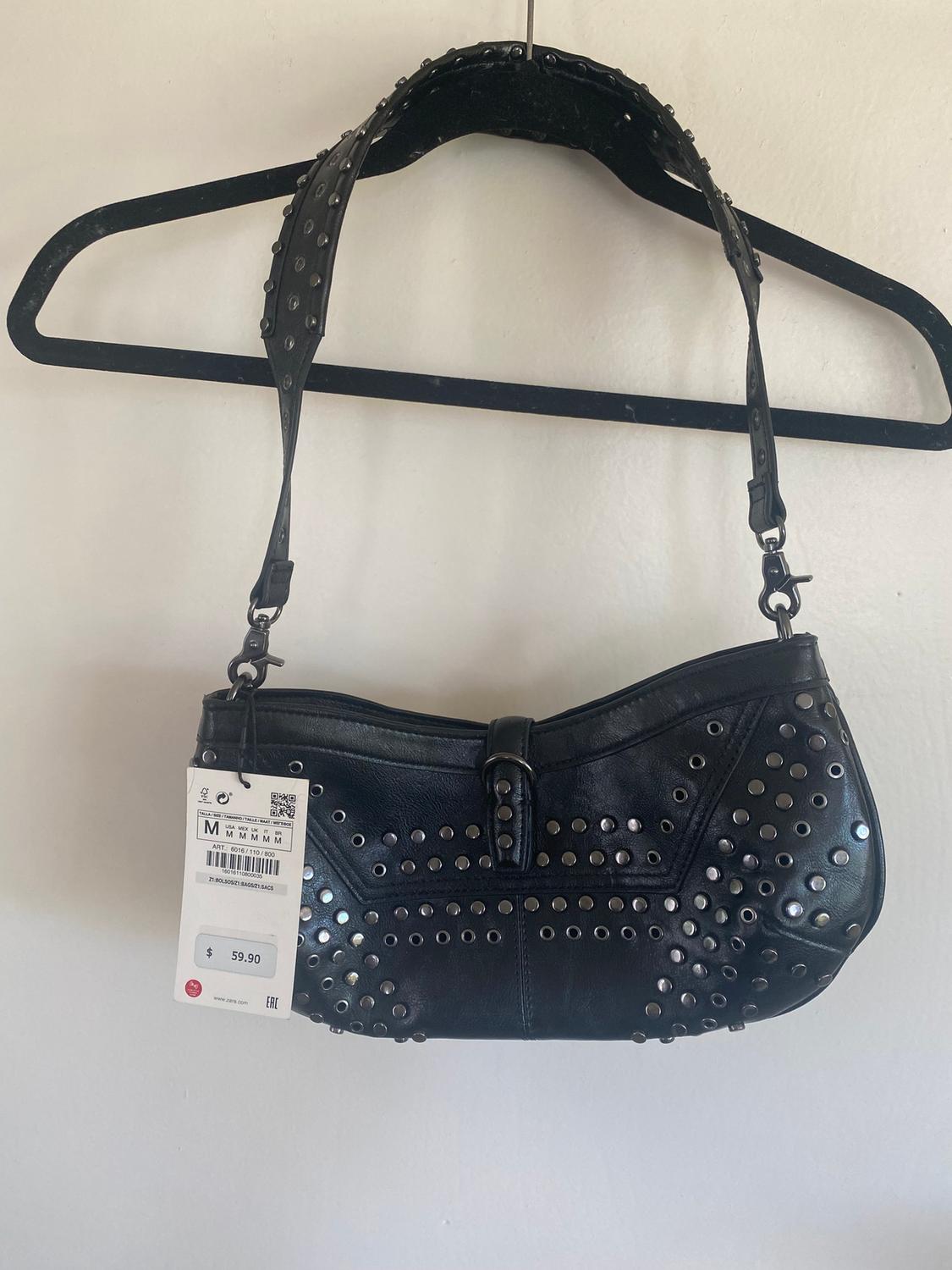Black handbag with silver studs hanging on a black hanger. Visible tag with price of $59.90. White background.