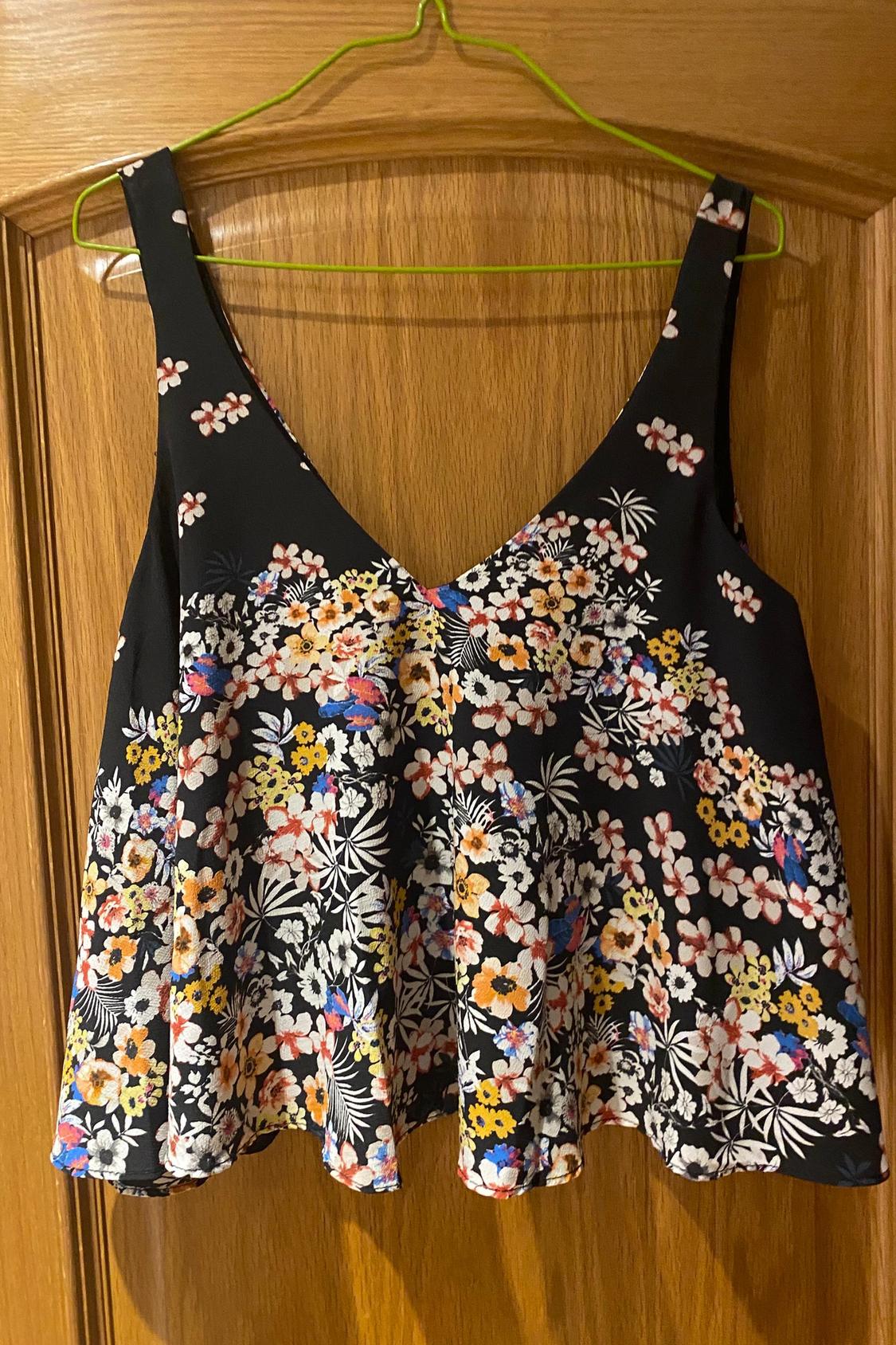 Front view of a black blouse with a multicoloured floral print and wide straps.
