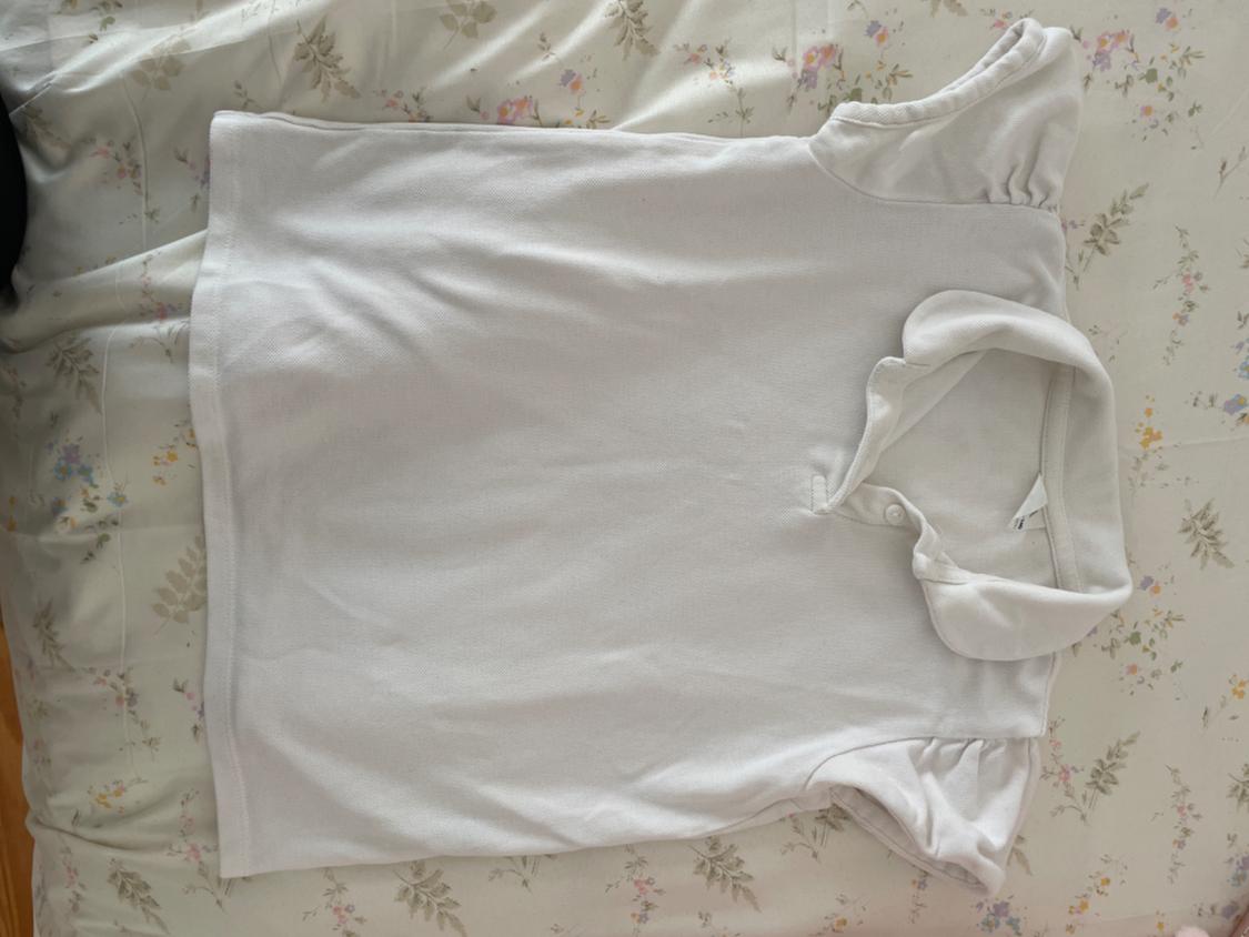 Front view of a white polo shirt with a classic collar and short sleeves.