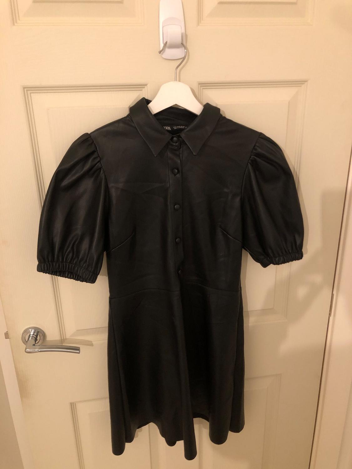 Front view of black dress with puffed sleeves and button-front.