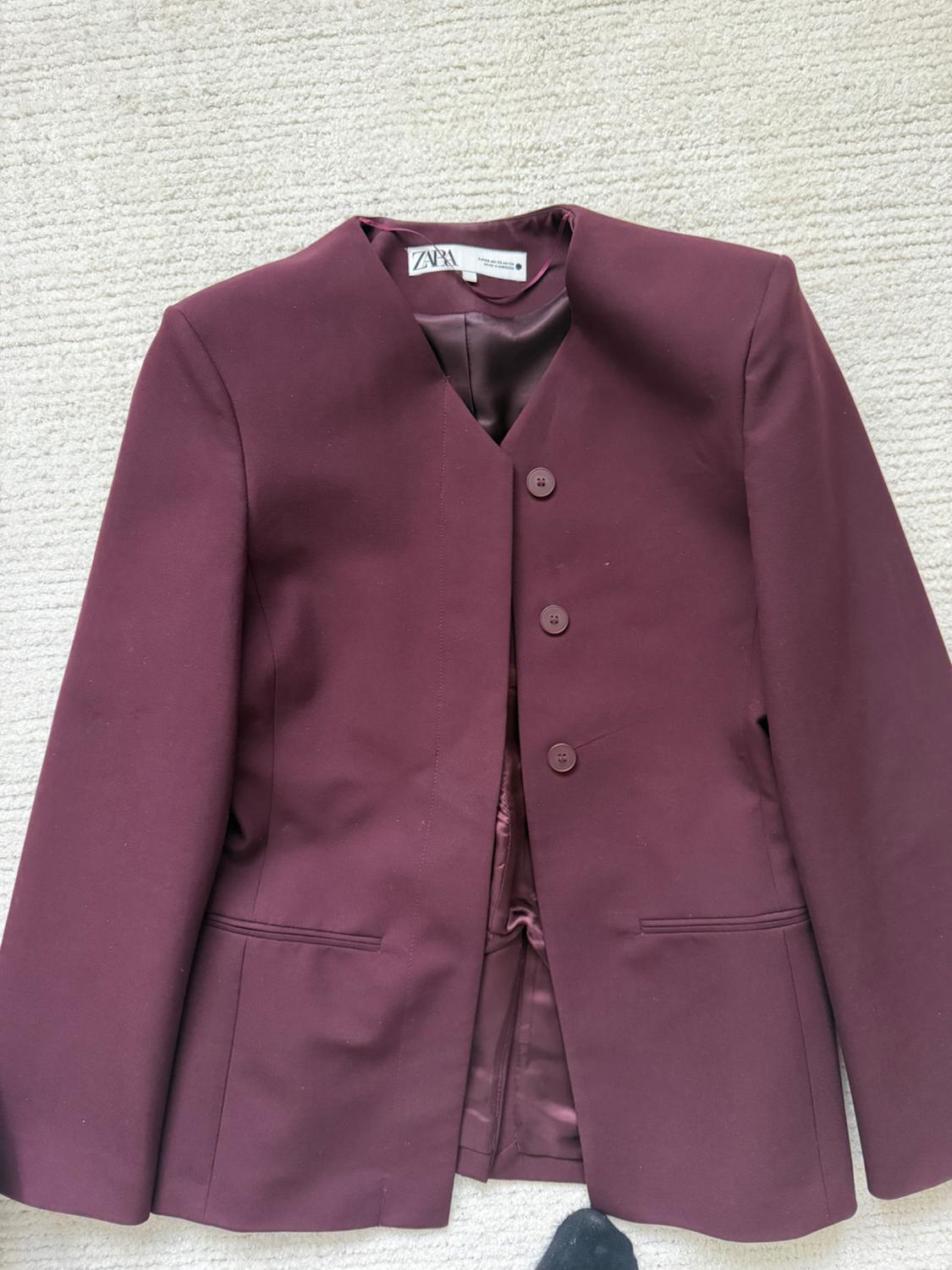 Women's burgundy jacket with three buttons and a round neck on a light carpet. Visible tag: ZARA.