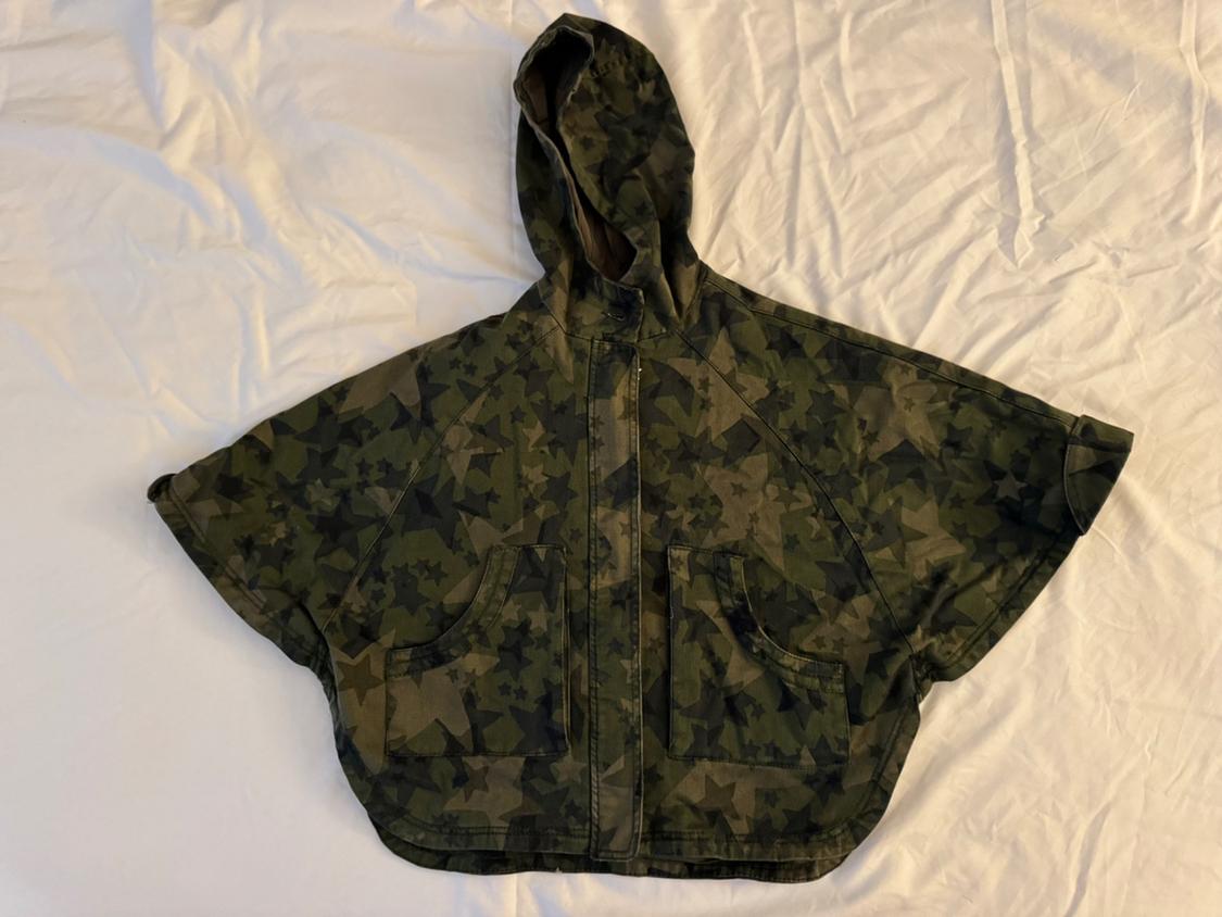 Front view of green camouflage cloak with hood and star print, front pockets.
