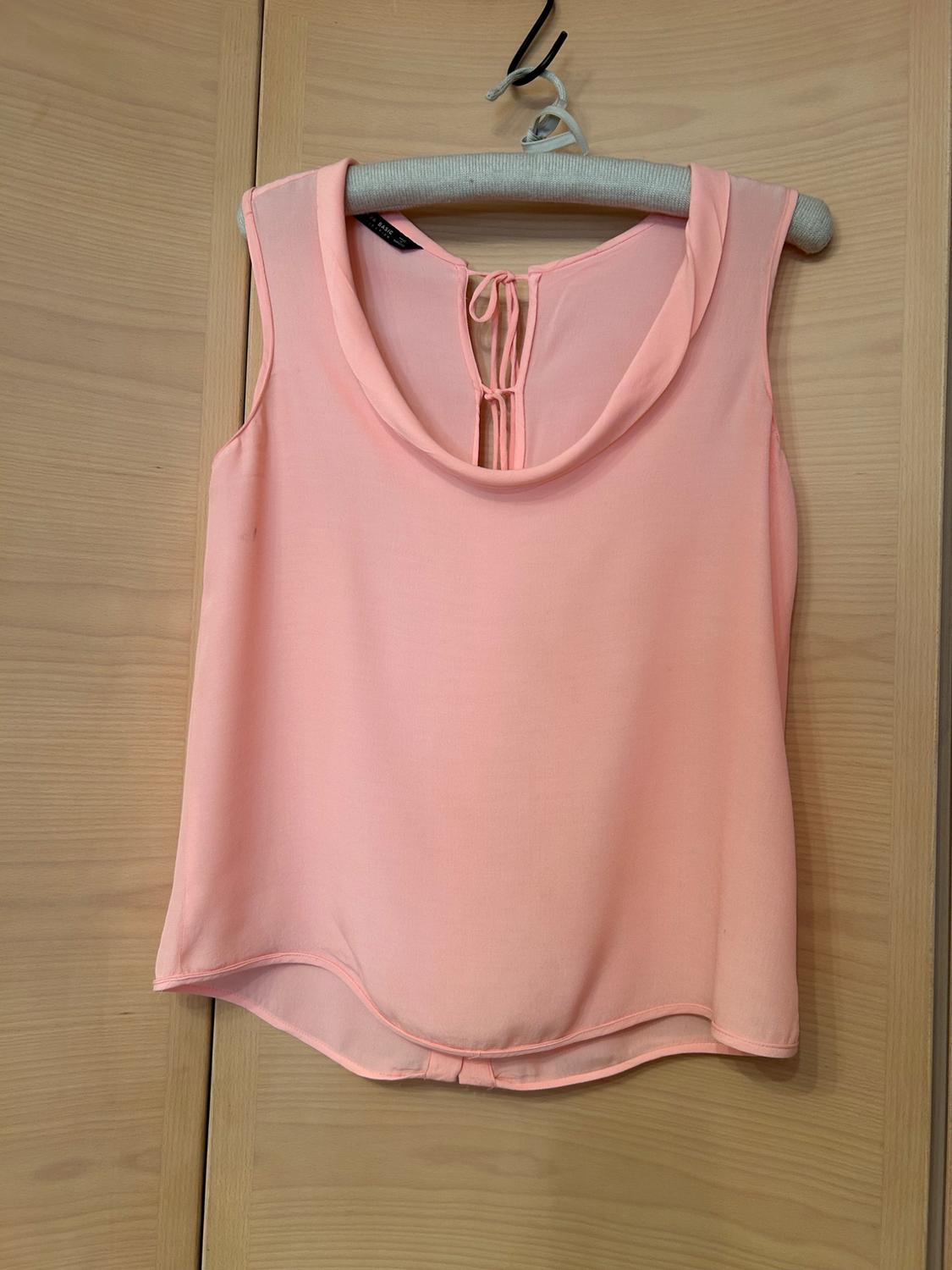 Front view of a pink sleeveless blouse with a round neckline and a bow detail at the neck.