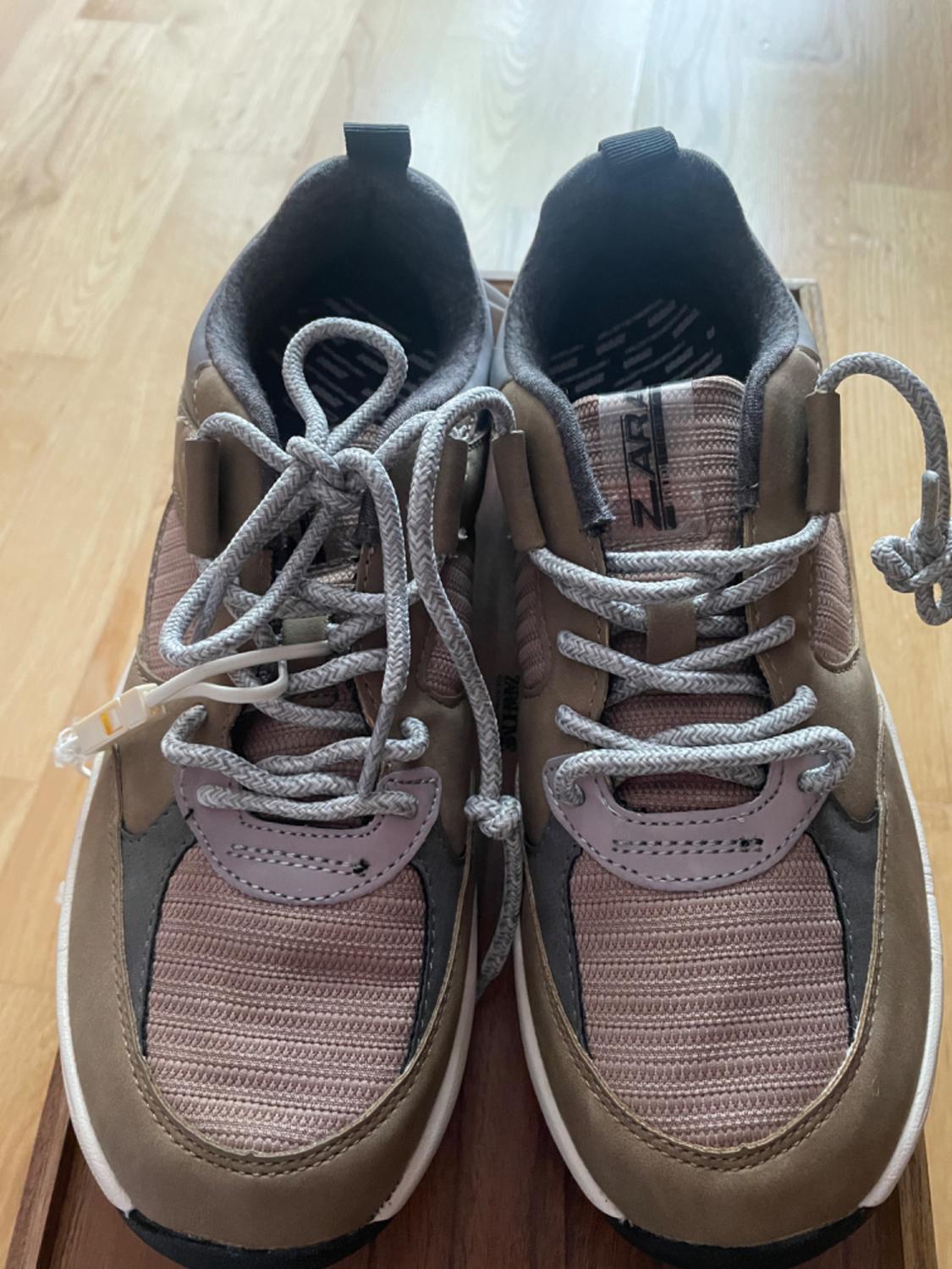 Top view of brown trainers with grey laces and 'Zara' text detail visible on the inside.