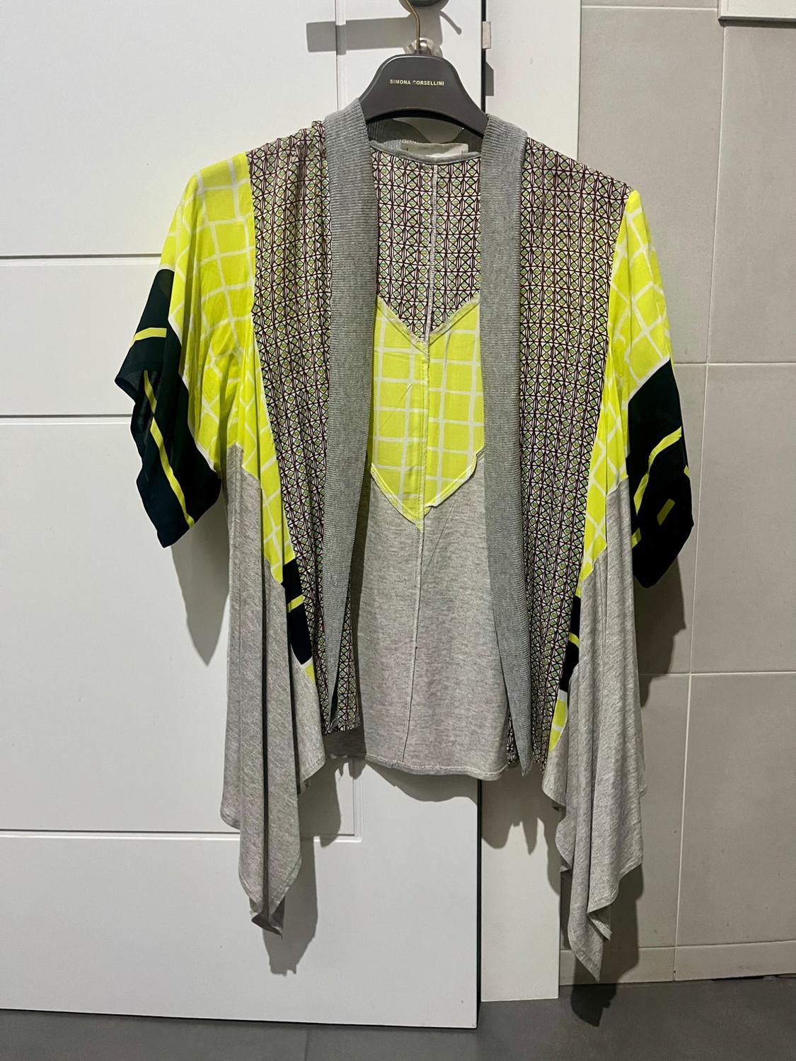 Jacket hanging on a black hanger with a geometric print in yellow and grey, against a white door and beige wall.