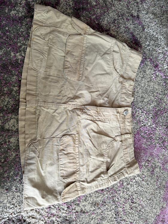 Beige skirt with large pockets on a gray and purple rug. Wrinkled fabric and visible texture.