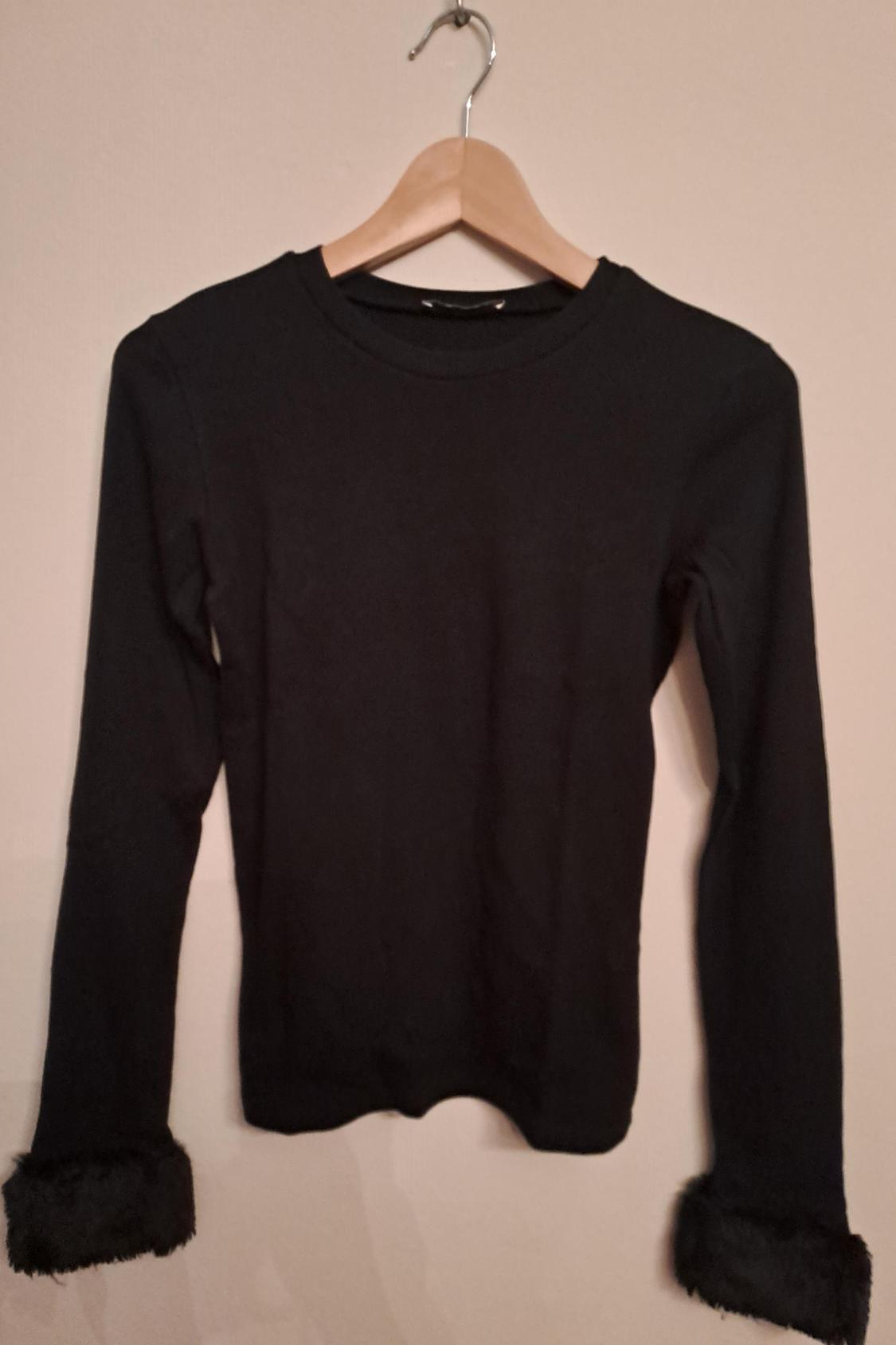 Front view of a black long-sleeved t-shirt with fur cuffs.