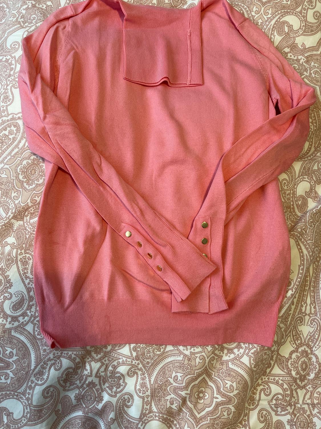Front view of pink jumper with buttons on the sleeves and square neck.