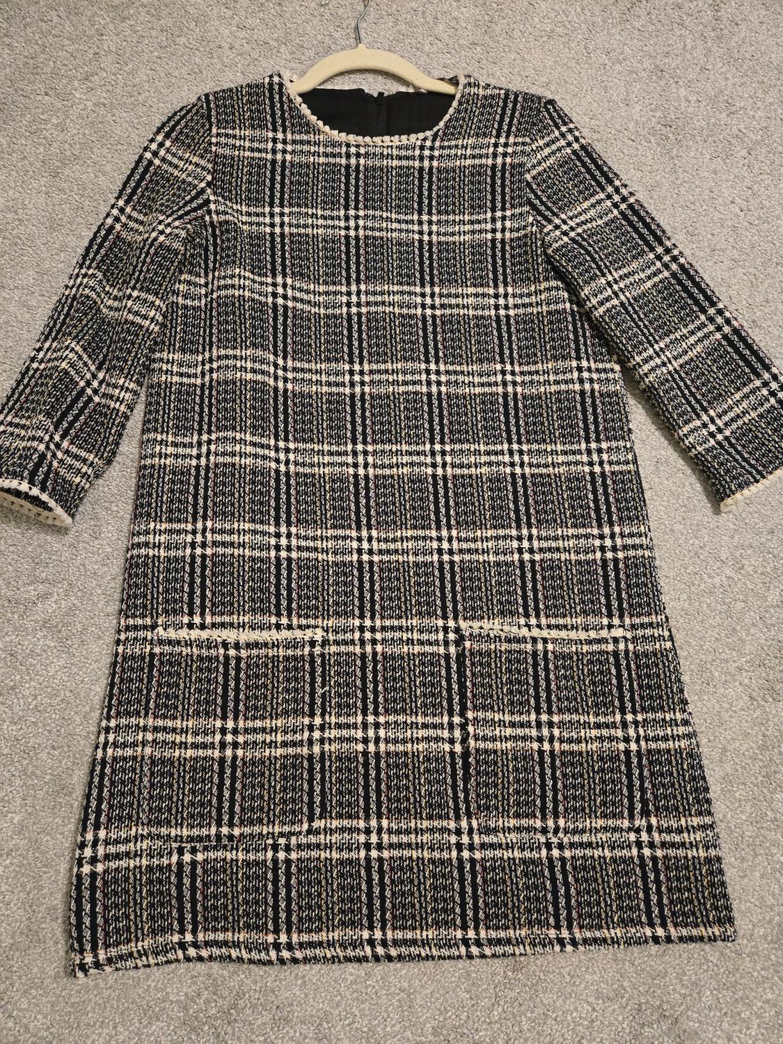 Front view of a plaid dress with front pockets and three-quarter sleeves.