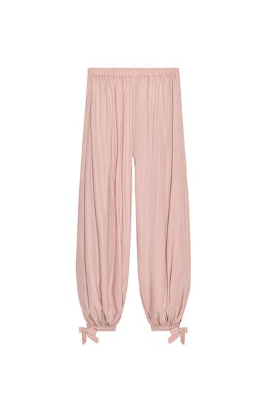 Front view of pink trousers with elasticated waistband and adjustable hems with ties.