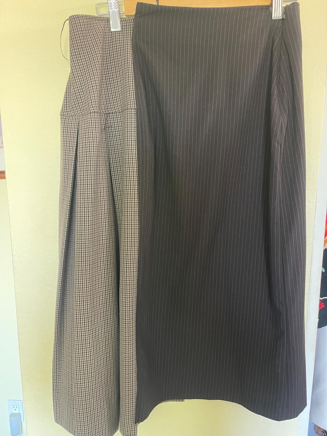 Skirt hung on a hanger, half with a small check print and half with fine vertical stripes, light beige background.