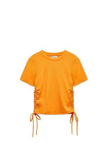 Orange short-sleeved T-shirt with a round neckline, side ruching, and ties. Label with Zara text. White background.