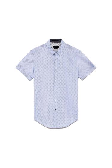 Light blue short-sleeved shirt with small dark polka dots and a button-down collar on a white background. Label with the text ZARA MAN.
