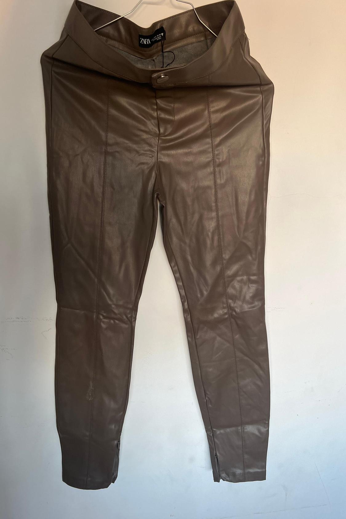 Front view of brown trousers with a wide waistband and button fastening.