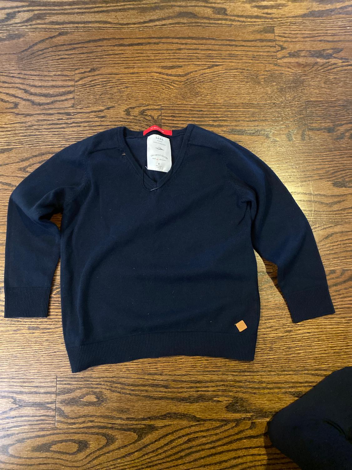 Front view of black V-neck sweater with hem detail.