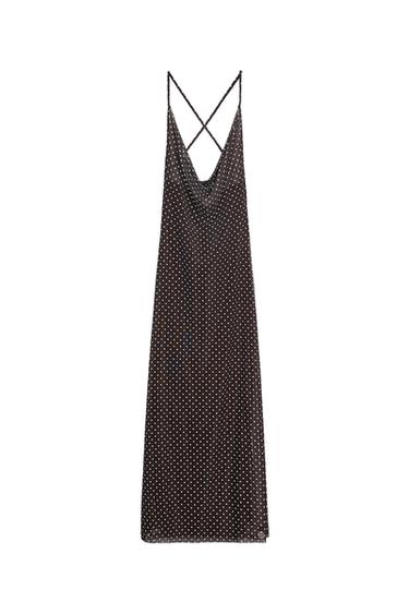 Long black dress with a white polka-dot print. Sleeveless design with thin crisscross straps at the back and a draped neckline.