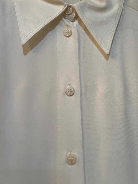 White satin fabric shirt with a classic collar and front buttons. The image shows a focus on the garment's details.