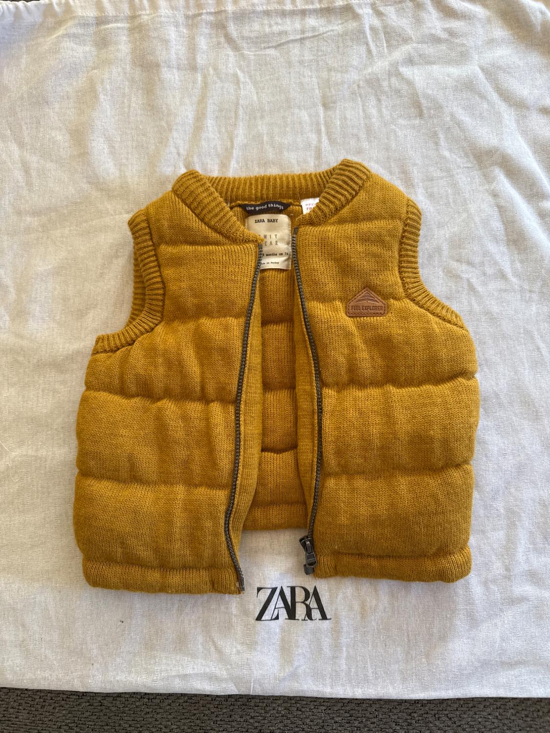 Mustard padded gilet for baby with zip, on a white bag with the black "ZARA" logo.