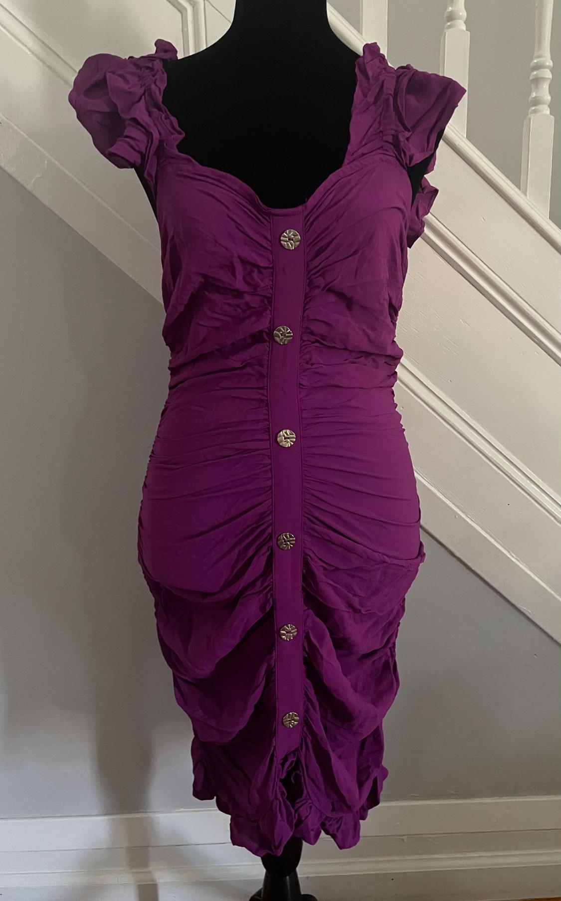 Purple dress with gold buttons on a black mannequin, positioned in front of a white staircase.
