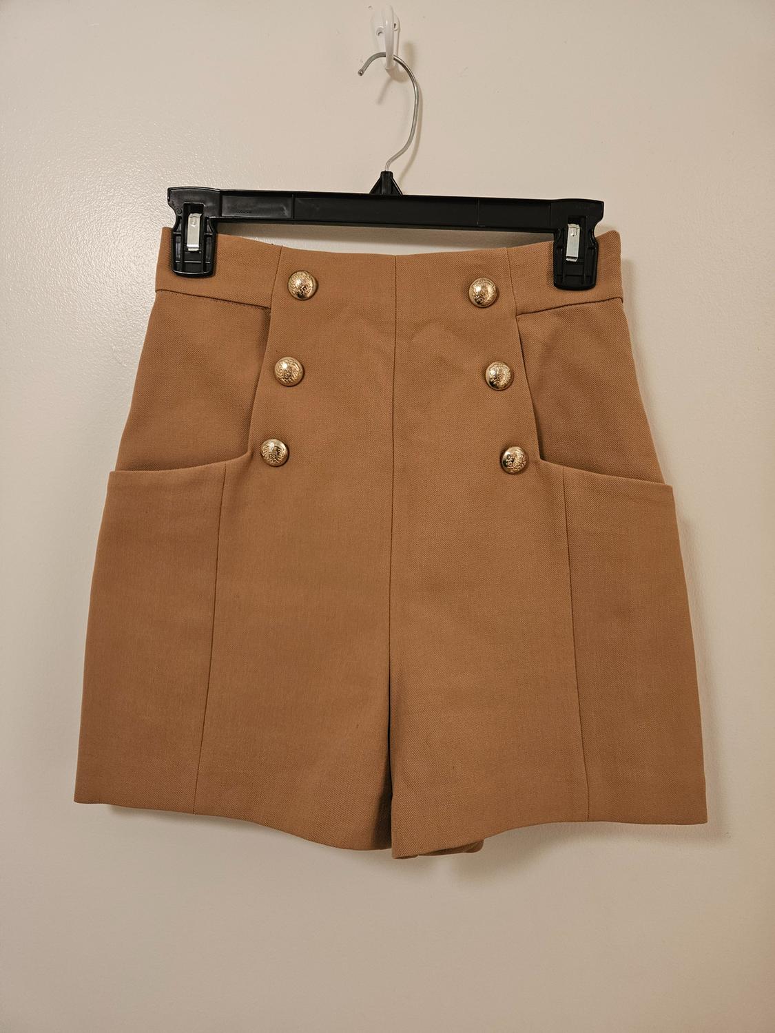 Front view of brown shorts with gold buttons and side pockets.