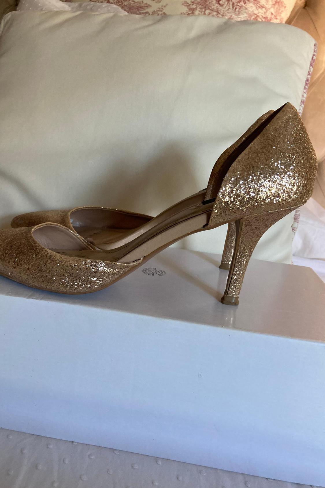 Gold glitter high heels on a white box.
