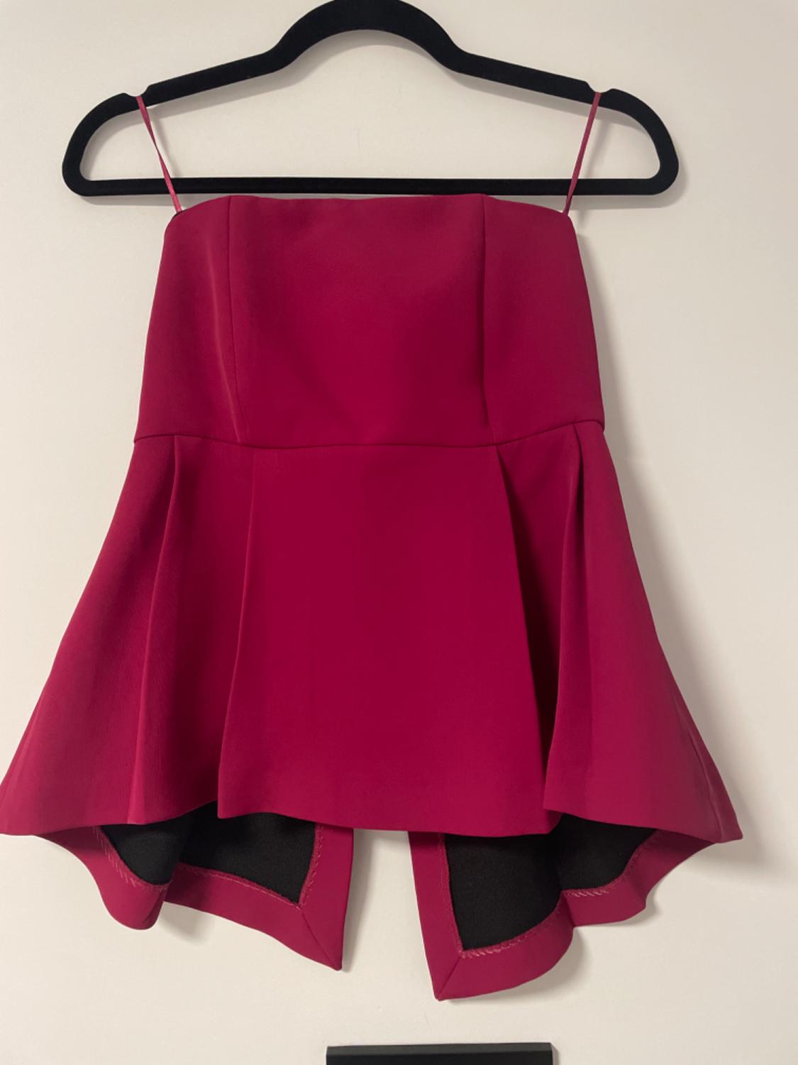 Red strapless top with an asymmetric hem, hanging on a black hanger against a white background.