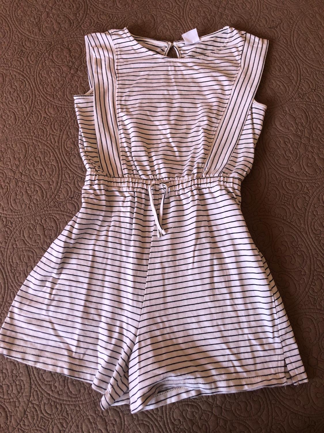 Black and white striped sleeveless jumpsuit with elasticated waist and tie, on a brown embossed design bedspread.