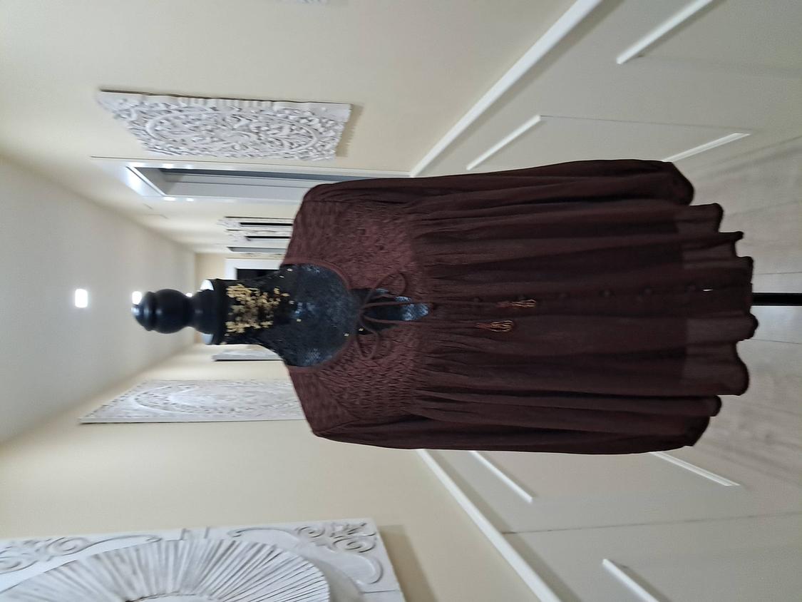 Mannequin in a light brown fabric dress in a corridor decorated with white wall panels.