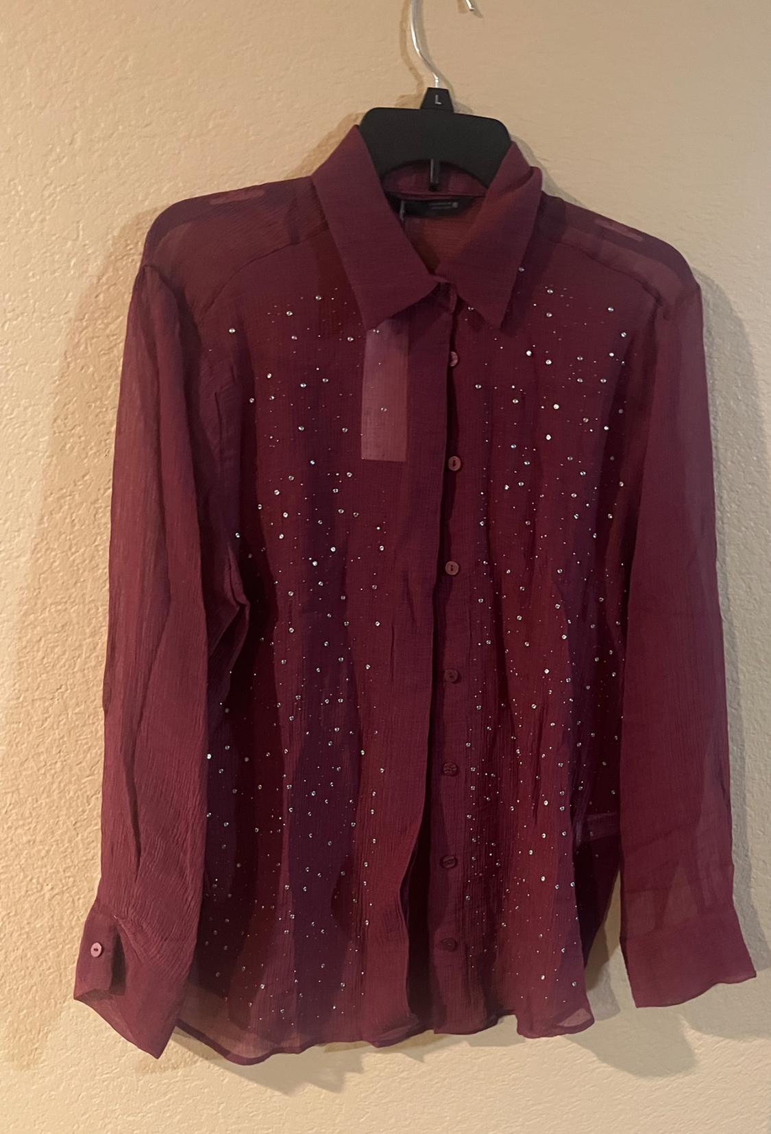 Burgundy shirt with a classic collar and buttons, decorated with small sparkly dots, hanging on a black hanger against a beige wall.