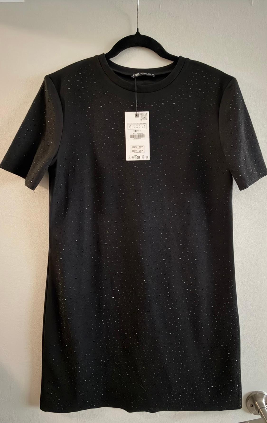 Black dress with small, sparkly studs, hanging on a black hanger. Visible tag with price of £39.99 and size S.