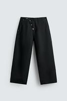 Front view of black wide-fit trousers with frog fastening, front and back patch pockets, washed effect.