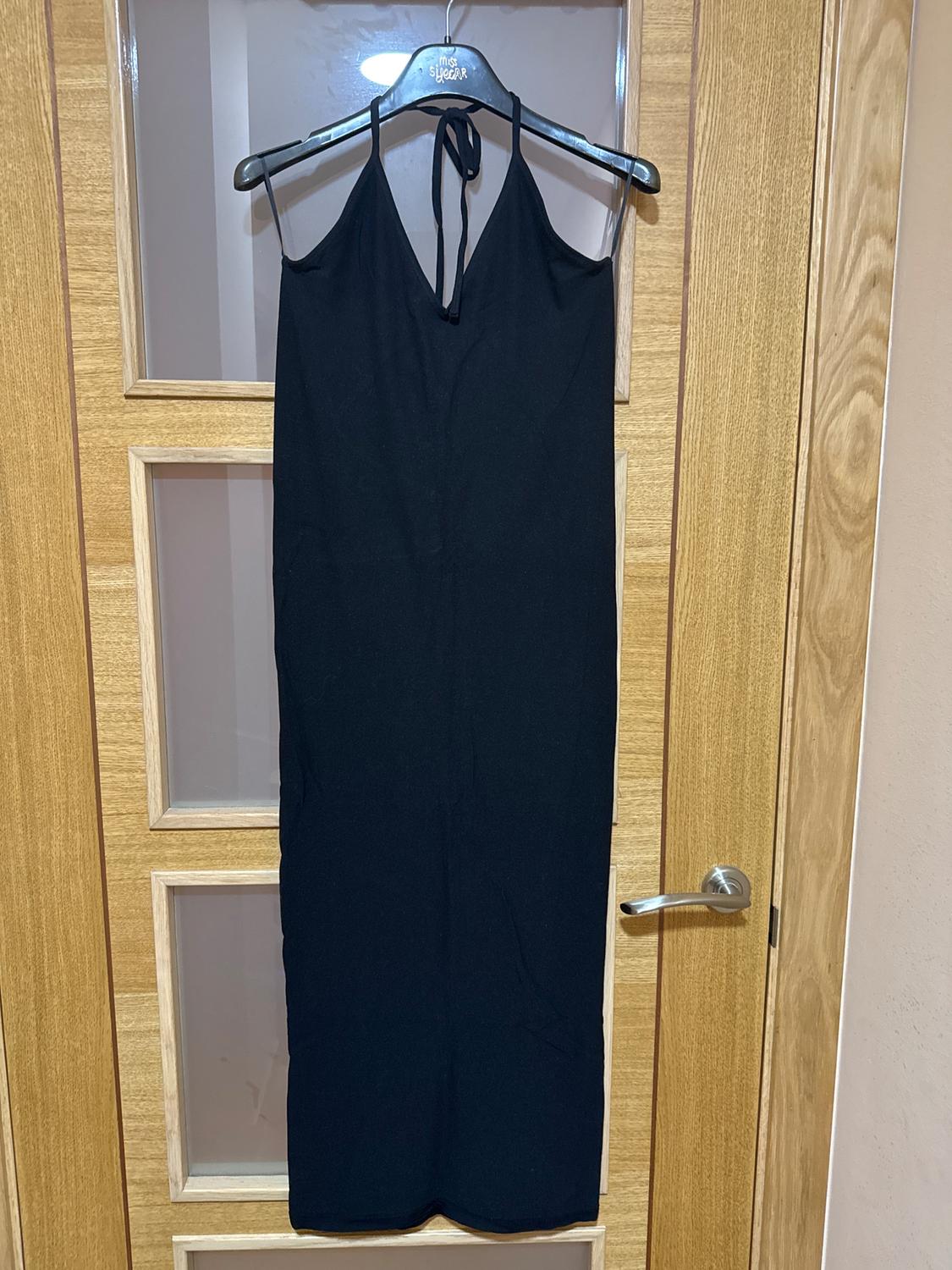 Black strappy dress hanging on a hanger with the inscription "my sugar", on a wooden door with glass panels.