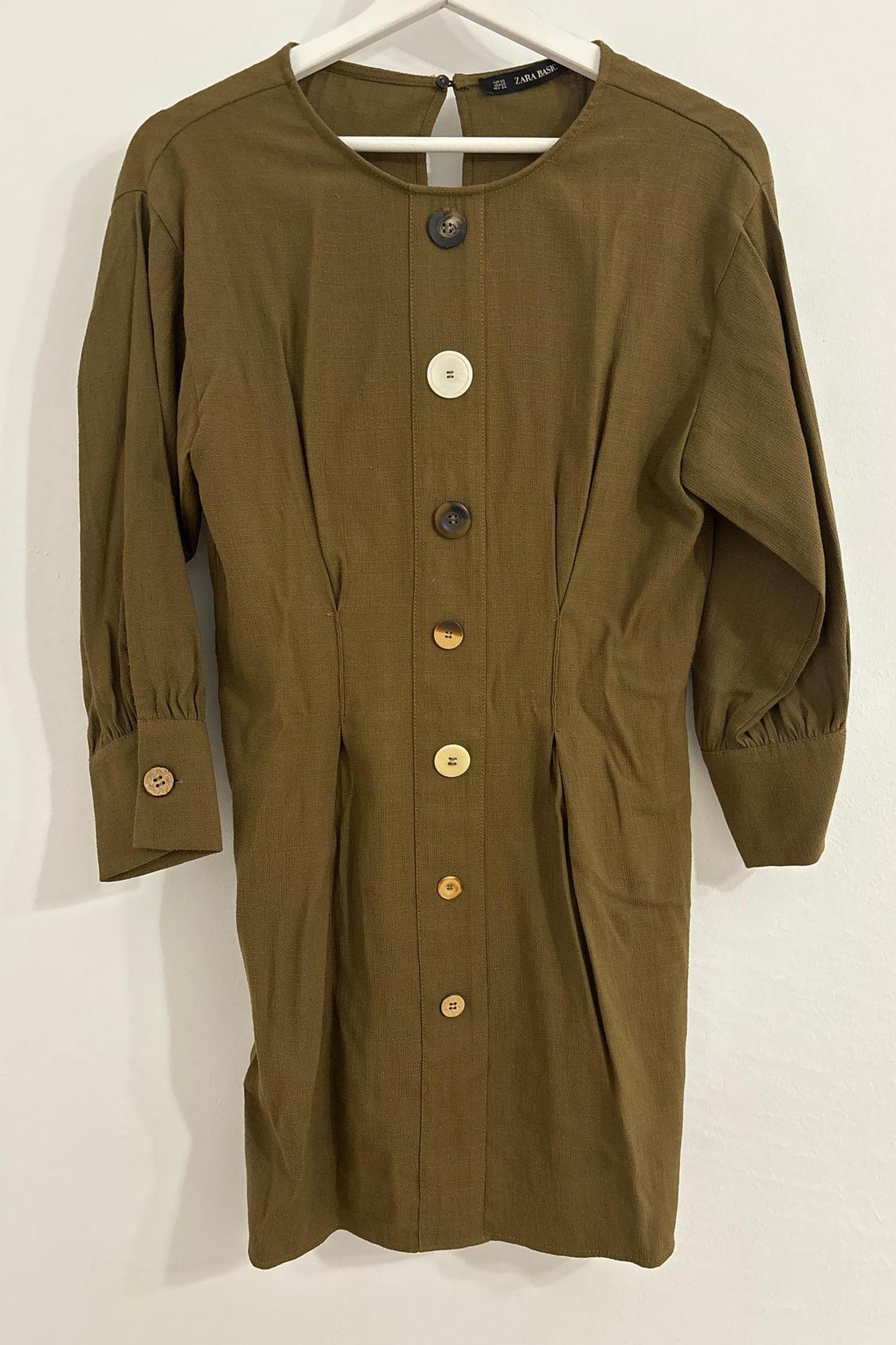 Front view of a brown dress with large buttons of different colours and long sleeves.