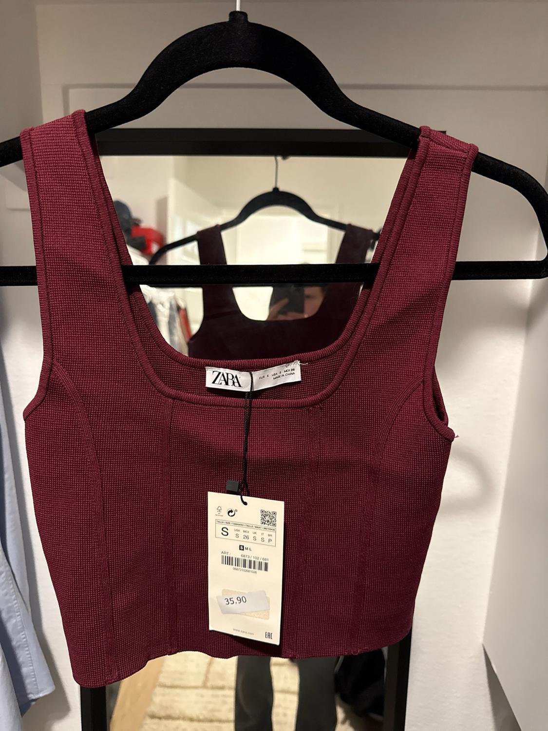 Short burgundy, fluted, square-neck top on a black hanger. Reflection in the mirror. Tags with text: ZARA, S, 35.90.